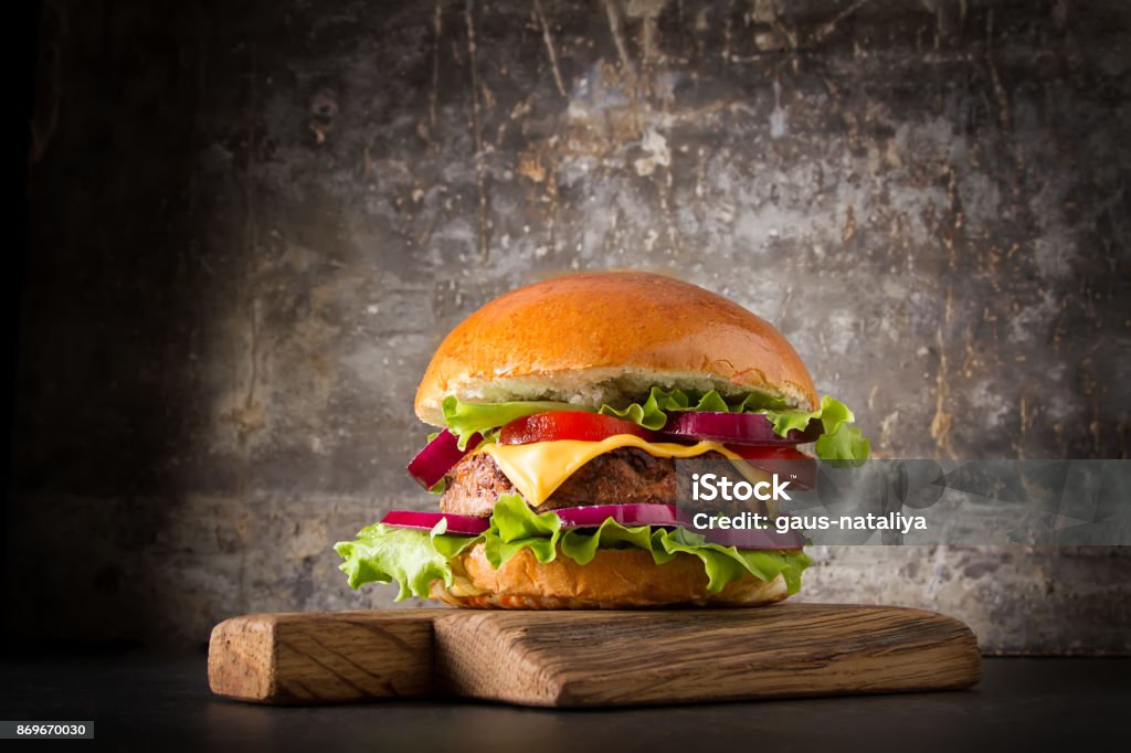 Burger with beef, cheese and tomatoes, American fast food. Gray background. Burger with beef, cheese and tomatoes, American fast food. Gray background Cheeseburger Stock Photo