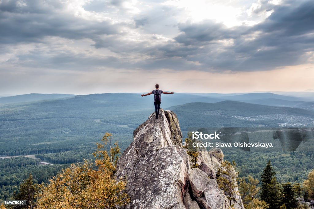 Um jovem em um pico de montanha. - Foto de stock de Pico da montanha royalty-free
