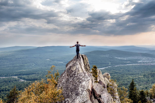 молодой человек на горной вершине. - rock human hand human arm climbing стоковые фото и изображения