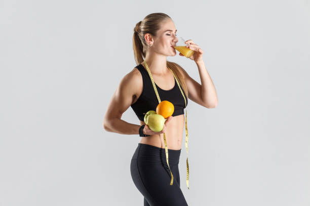 chica joven con frutas y jugo de naranja beber - instructor one person fruit drinking fotografías e imágenes de stock