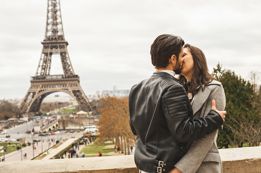 Young couple kissing in the most romantic spot in Paris. They are enjoying their honeymoon.