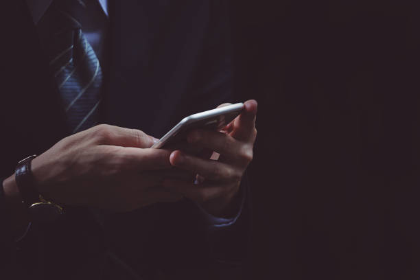 istock Businessman hand using smartphone in black background 869693660