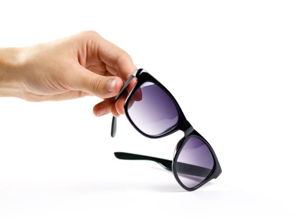 istock Hand holds black sunglasses. Isolated on white background 869693840