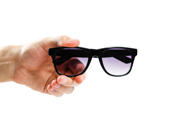 Hand holds black sunglasses. Isolated on white background.
