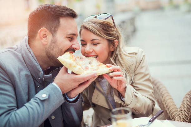 istock Love couple in a restaurant eating pizza. 869695370