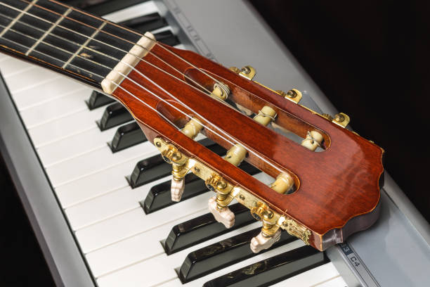 istock Guitar headstock on the piano keyboard 869698136