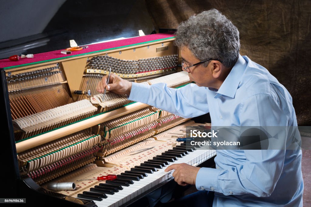 Instrument technician tuning piano Instrument technician tuning a piano. Piano Tuner Stock Photo