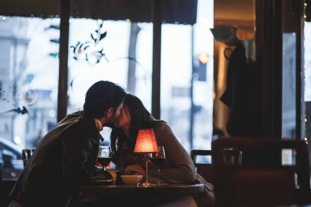 Two lovers are kissing in city cafe. They are enjoying this special moment of togetherness.