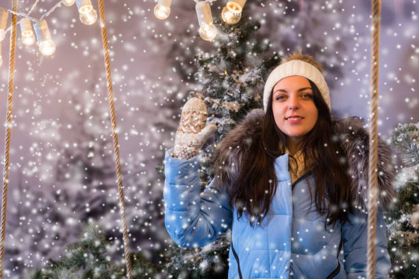 istock Attractive woman in blue down jacket greeting somebody in a snow-covered park while snowing 869710702