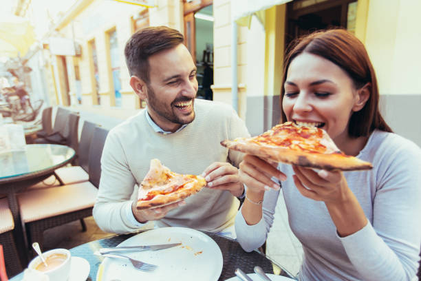 istock Love couple in a restaurant eating pizza. 869740578