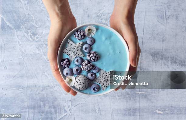 Womans Hands Holding Blue Spirulina Yogurt Smoothie Bowl With Berries And Dragon Fruit Stock Photo - Download Image Now