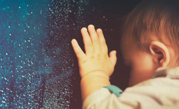 istock Baby looking through rainy window at home 869750568
