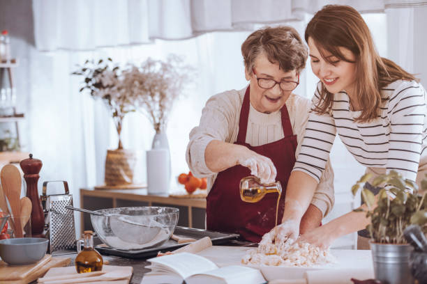 祖母の生地に油を追加します。 - grandmother domestic life cooking domestic kitchen ストックフォトと画像