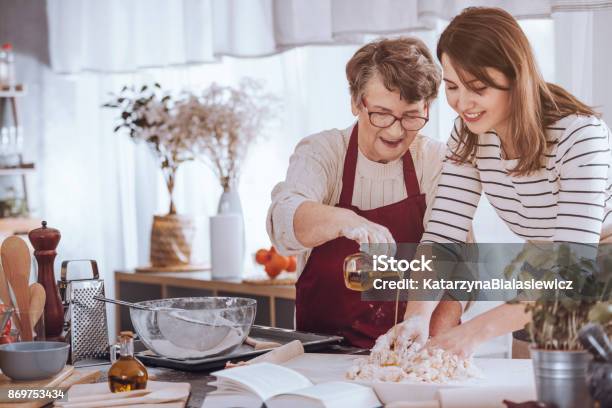 Grandmother Adding Oil To Dough Stock Photo - Download Image Now - Christmas, Cooking, Grandmother