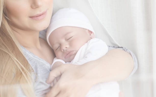 istock Gentle mother holding in hands her newborn sleeping baby 869753680