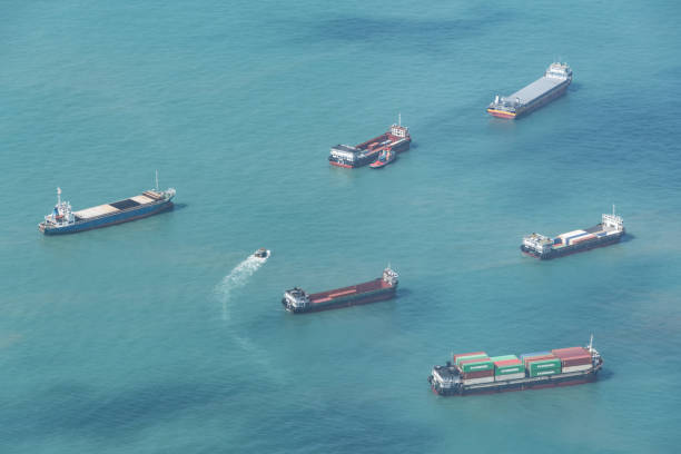 Six large cargo ships and one small tug boat at sea with shipping containers.
