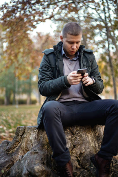 istock Young handsome man using smart phone in autumn park 869762608
