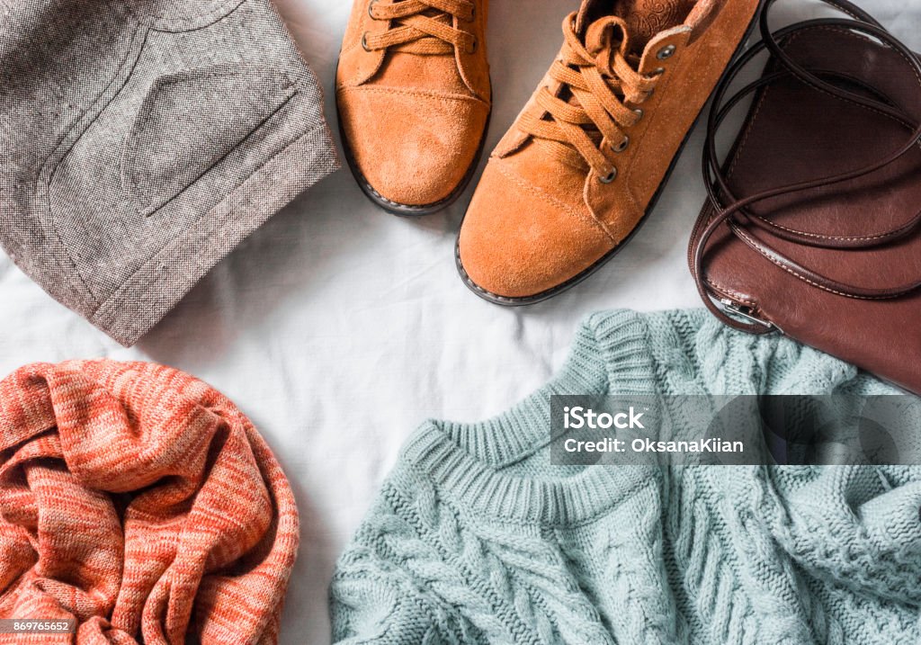 Women's clothing set - skirt, suede boots, sweater, scarf, leather cross body bag on a light background, top view. Winter, fall female clothing Clothing Stock Photo
