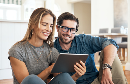 Cropped shot of an affectionate young couple using their tablet while sitting on a sofa at home