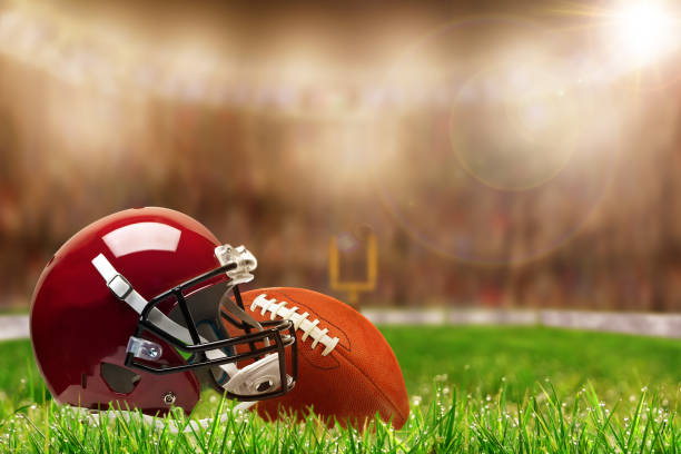 Football Equipment on Grass With Copy Space Low angle view of football helmet and ball on field grass and deliberate shallow depth of field on brightly lit stadium background with lens flare and copy space. Fictitious stadium background was created entirely from scratch in Photoshop. football helmet and ball stock pictures, royalty-free photos & images