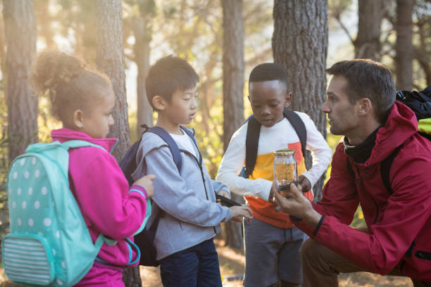istock Teacher and kids examining plant in jar 869779418