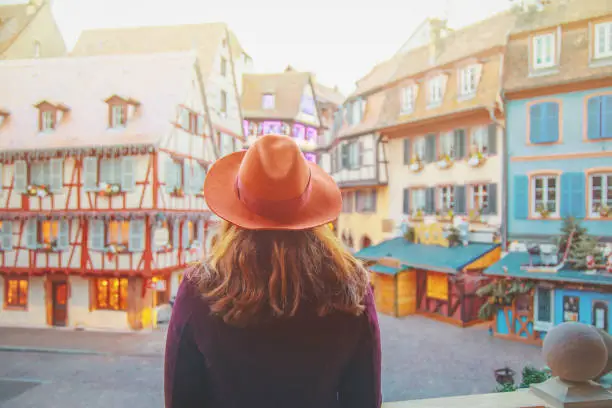 Young happy female enjoying Christmas in Old town illuminated and decorate magical like a fairy tale in Noel festive season in Colmar, Alsace, France