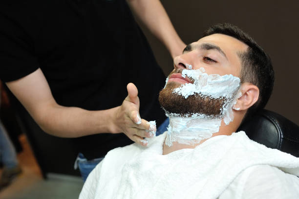 istock Barber preparing man face for shaving with hot towel 869786550