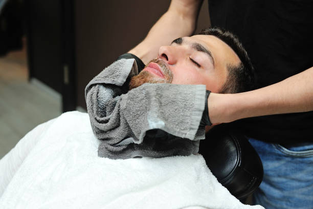 Barber preparing man face for shaving with hot towel stock photo