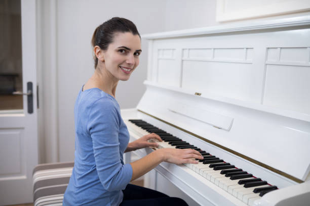 Senior woman sitting at a piano, with sheet music playing the piano and singing. Image shot with, Canon 5D Mark2, 100 ISO, 24-115mm lens and studio strobes.