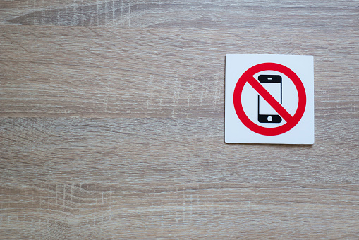 no phone allowed sign on wooden wall with space for adding text on the left side