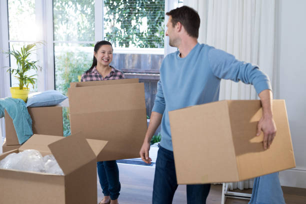istock Couple carrying big cardboard box at new home 869818768