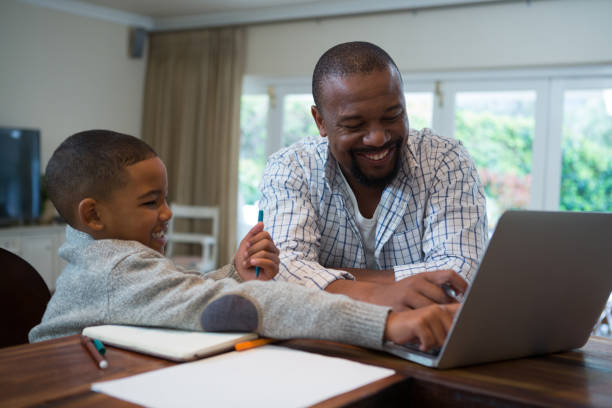 istock Father and son using laptop in living room 869829534