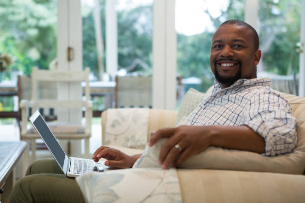 istock Man using laptop on sofa in living room 869829778