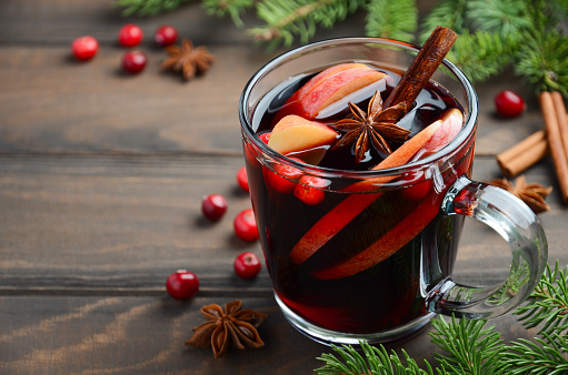 Christmas Mulled Wine with Apple and Cranberries. Holiday Concept Decorated with Fir Branches, Cranberries and Spices. Selective Focus Copy Space.