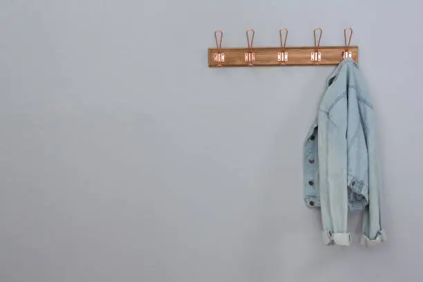 Denim jacket hanging on hook against wall