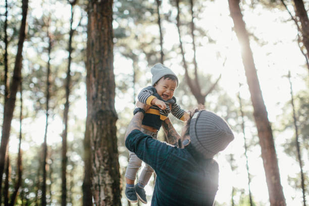 istock Father holding his son in forest in sunset. 869840980