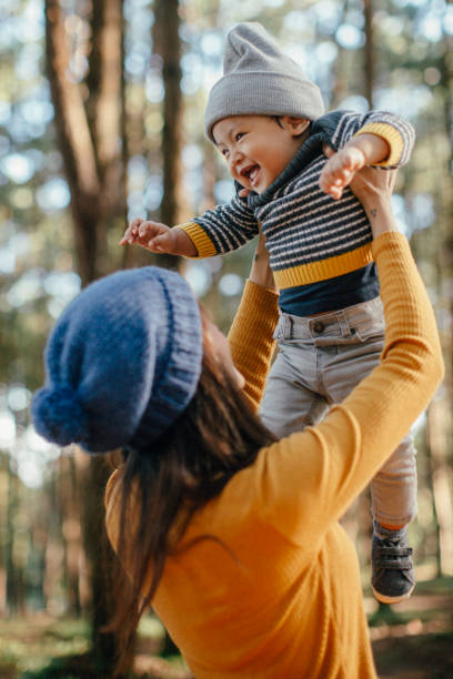 Mother holding his son in forest in sunset.