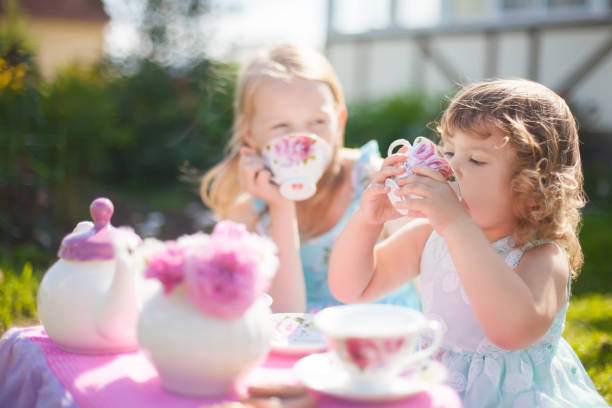 dos hermanas jugando partido de té al aire libre. - tea party party tea little girls fotografías e imágenes de stock