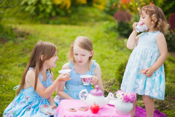 istock Three sisters playing tea party outdoors. 869843208