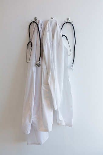 Laboratory coat and stethoscope hanging on hook against wall