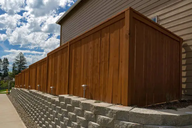 Photo of Wood fence cement stack stone blocks retaining wall and landscaping lighting