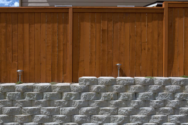 istock Wood fence cement stack stone blocks retaining wall and landscaping lighting front view 869845948