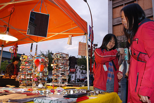 Chinese girls selling  bijouterie at the night market in Chinatown, Vancouver.