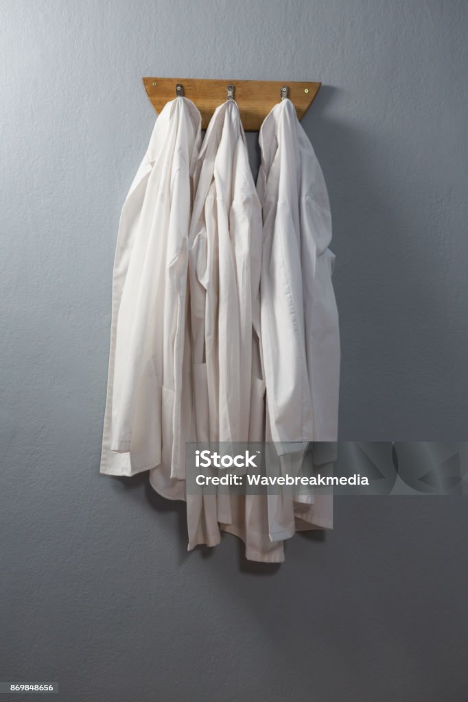 Laboratory coat hanging on hook Laboratory coat hanging on hook against wall Doctor Stock Photo