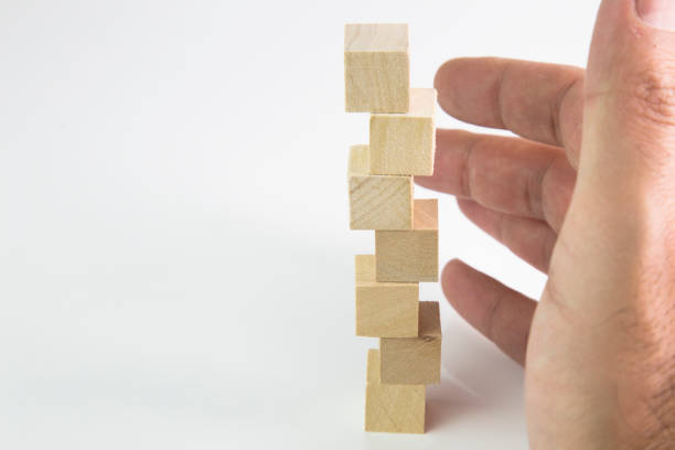 istock front view of male hand placing and positioning wooden blocks in various structures. 869848726