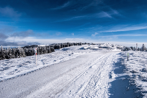 winter Fischbacher Alpen mountains with snow covered hiking trail, hills and blue sky with clouds in Styria (Austria)