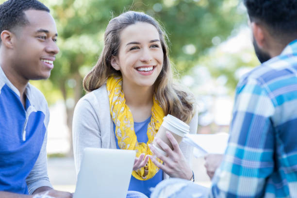 istock Young female college student sits outside with classmates 869862534