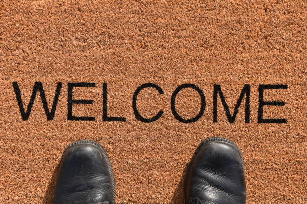 istock Pair of legs standing on a doormat 869875684