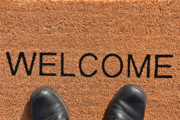 istock Pair of legs standing on a doormat 869875702