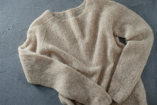 Pastel beige knitted woolen sweater on a hanger